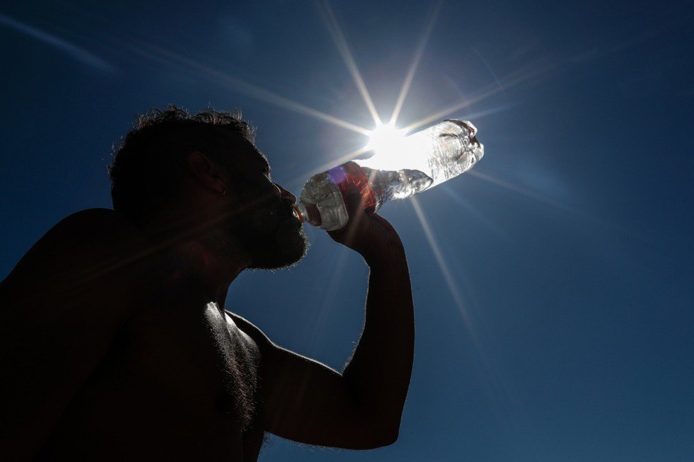 Чоловік п’є воду у розпал спеки на пляжі Копакабана в Ріо-де-Жанейро, 19 вересня 2023 р.