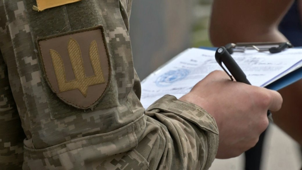 Представник ТЦК вписує дані у повістку для військовозобов'язаного.
