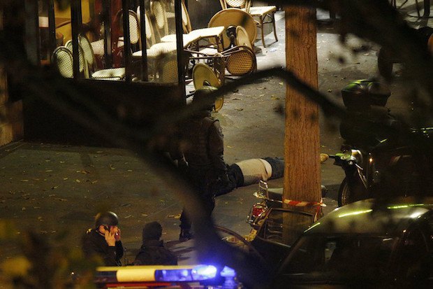 Полицейский стоит возле тела погибшего у концертного зала Батаклан