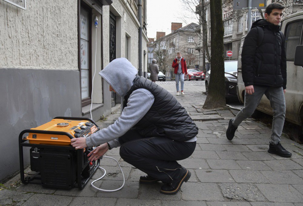 Чоловік вмикає генератор на вулиці у Львові.