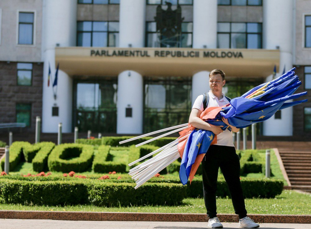 Учасник акції тримає прапори після маршу молоді PAS перед парламентом Молдови в Кишиневі, 1 червня 2024 року.