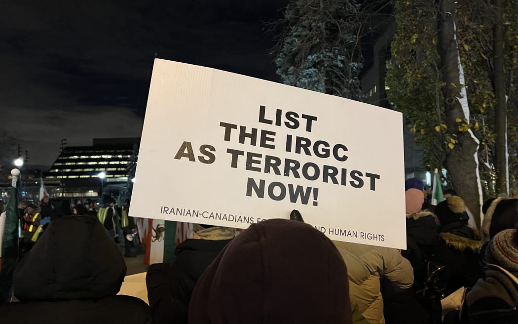 Учасник акції протесту в Торонто тримає табличку з проханням до уряду Канади визнати Корпус вартових Ісламської революції терористичною організацією. 