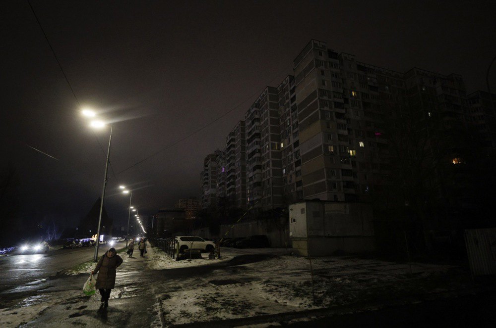 Люди йдуть темною вулицею під час відключення електроенергії в Києві