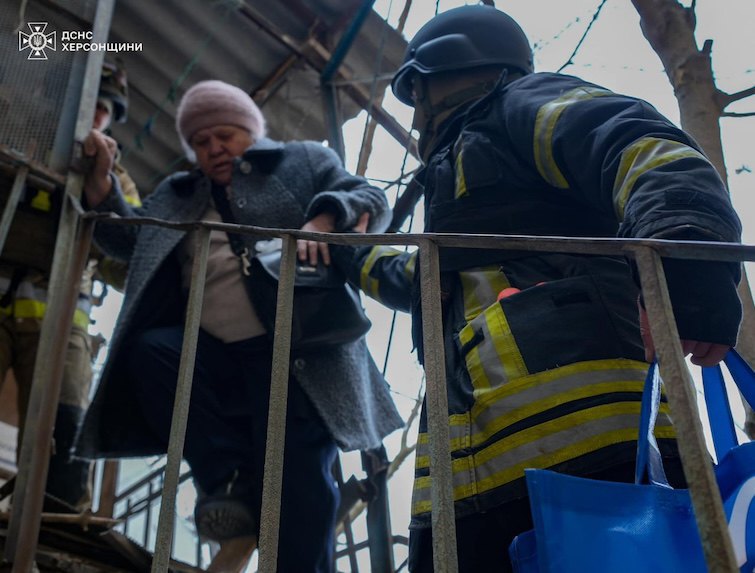 Рятувальники виводять постраждалу з пошкодженої російським ударом оселі 