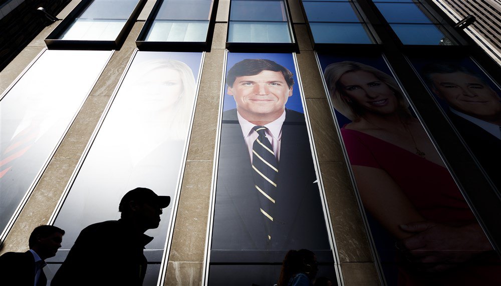 Постер з фото телеведучого Fox News Такера Карлсона (в ценрті) біля студії Fox News у будівлі News Corporation у Нью-Йорку.