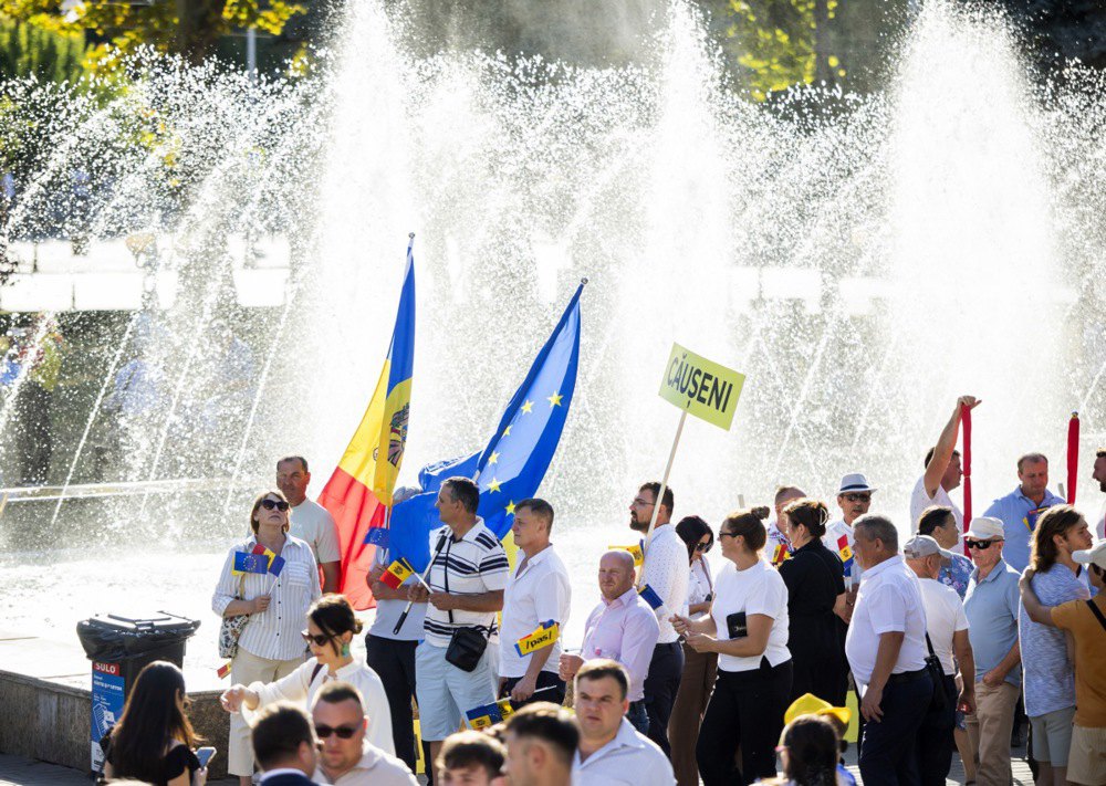 Люди з прапорами Молдови та ЄС під час передвиборчої кампанії партії PAS перед будівлею Національної опери в Кишиневі, 29 серпня
2025 року