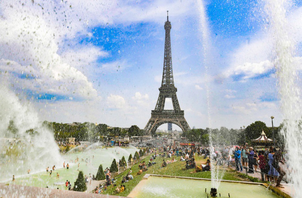 Люди купаються у фонтані Трокадеро перед Ейфелевою вежею в Парижі.