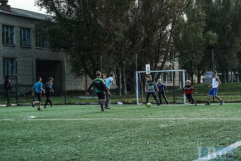 Дети играют в футбол возле школы в Новолуганском. До войны тут училось 1200 школьников, сейчас – две сотни. Не хватает и
учителей, говорят местные жители. Сейчас на пенсию ушел учитель истории, поэтому один учитель читает по несколько предметов