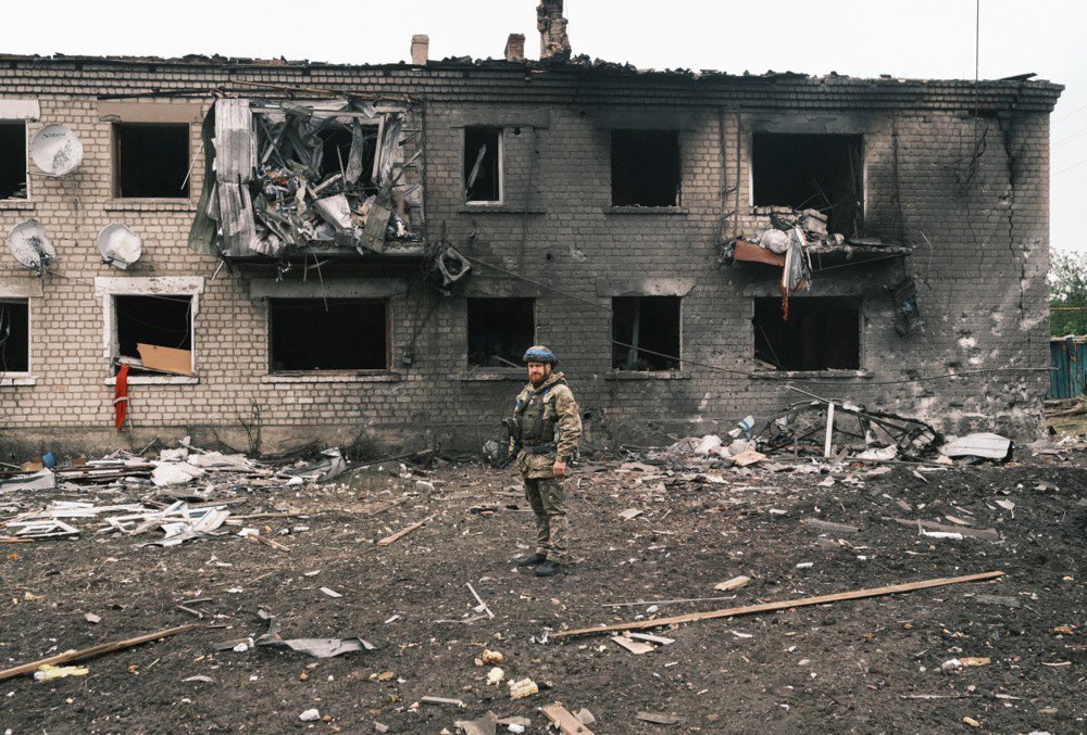 Український поліцейський оглядає пошкоджену будівлю під час евакуації місцевого населення