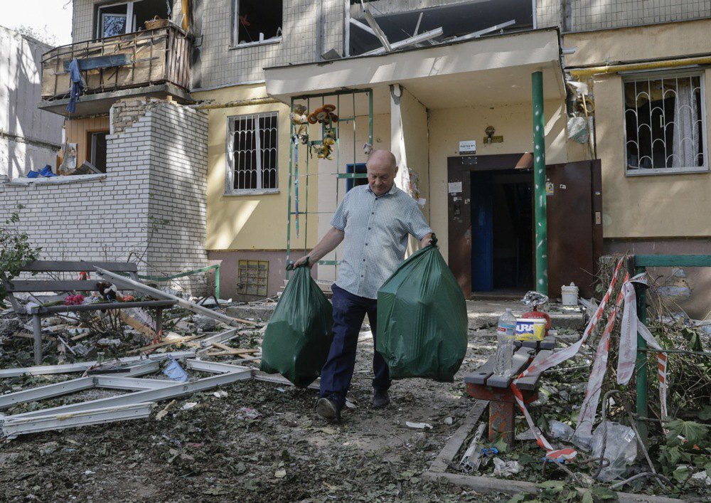 Мешканець будинку виносить уцілілі речі з пошкодженого будинку на Кучера, 2-А
