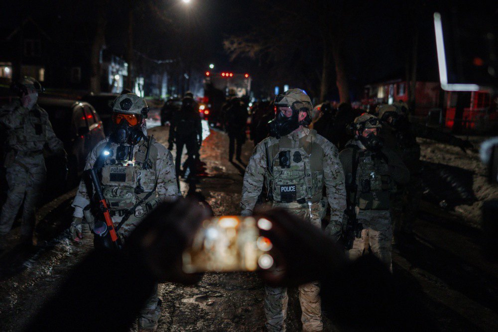 Член громади знімає на відео співробітників федеральної імміграційної служби, які відступають від натовпу під час протесту у Міннеаполісі, 14 січня 2026 року.