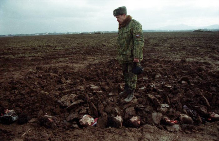 Російський солдат крокує по тілах чеченців у братській могилі в с. Садікурт, Чечня, лютий 2000 року