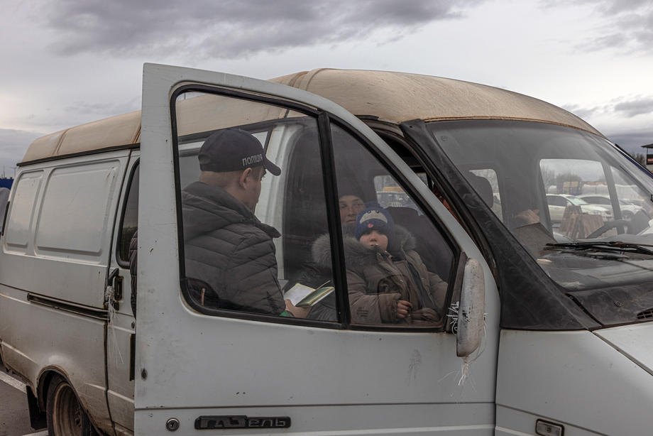Співробітник поліції перевіряє документи пасажирів мікроавтобуса з окупованих територій на блокпосту дорогою до пункту евакуації в Запоріжжі, 21 квітня 2022 року.