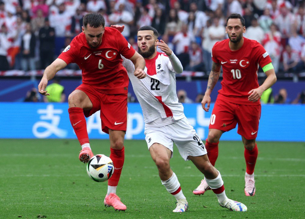 Оркун Коеккуе з Туреччини (ліворуч) у боротьбі проти Джорджа Мікаутадзе з Грузії (праворуч), а Хакан Чалханоглу з Туреччини спостерігає за футбольним матчем групи F УЄФА Євро-2024 між Туреччиною та Грузією в Дортмунді, Німеччина.