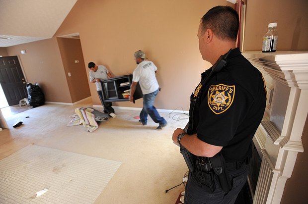Шериф наблюдает, как носильщики выносят имущества жильцов, выселяемых из-за несвоевременно выплаченной аренды в Вифлееме, штат
Пенсильвания, США 