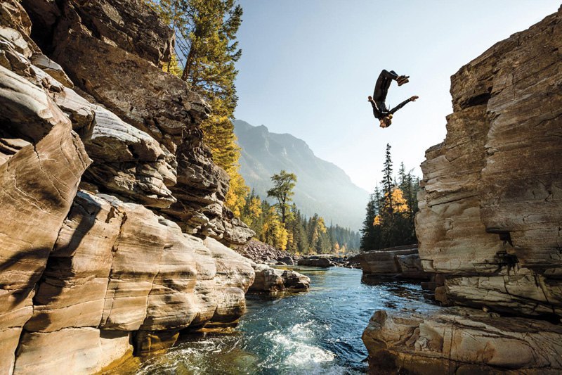 Стивен Донован прыгает со скалы в реку в Национальном парке Глейшер, куда он устроился на сезонную работу, Канада.