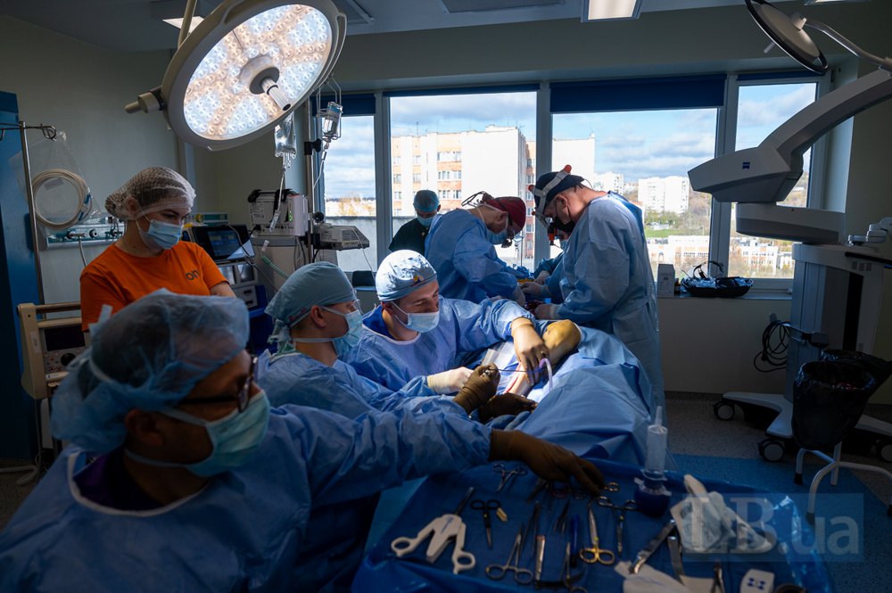 Дві бригади хірургів працюють над пацієнтом — трансплантують частини кістки з ноги на обличчя.