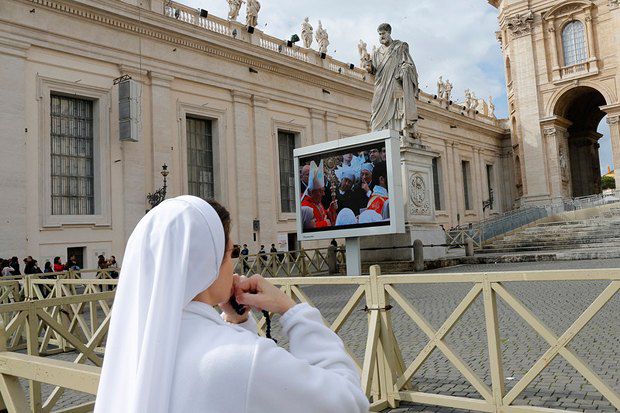 Монашка на площади Святого Перта следит за трансляцией мессы в базилике Святого Петра