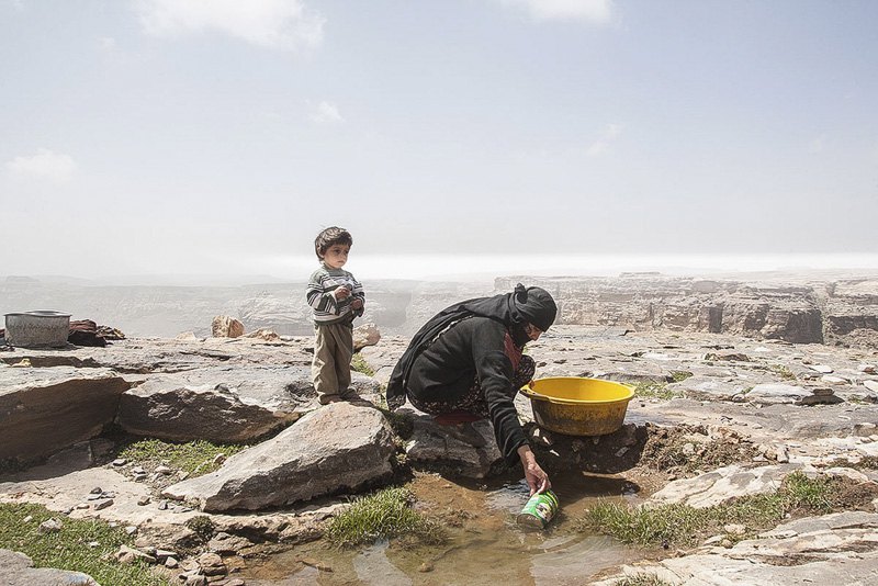 Мать с ребенком собирают воду, оставшуюся в луже после дождя. У семьи нет колодца, и ее выживание полностью зависит от дождевой
воды. Йемен переживает водные кризисы, которые считаются одними из самых тяжелых в мире. 