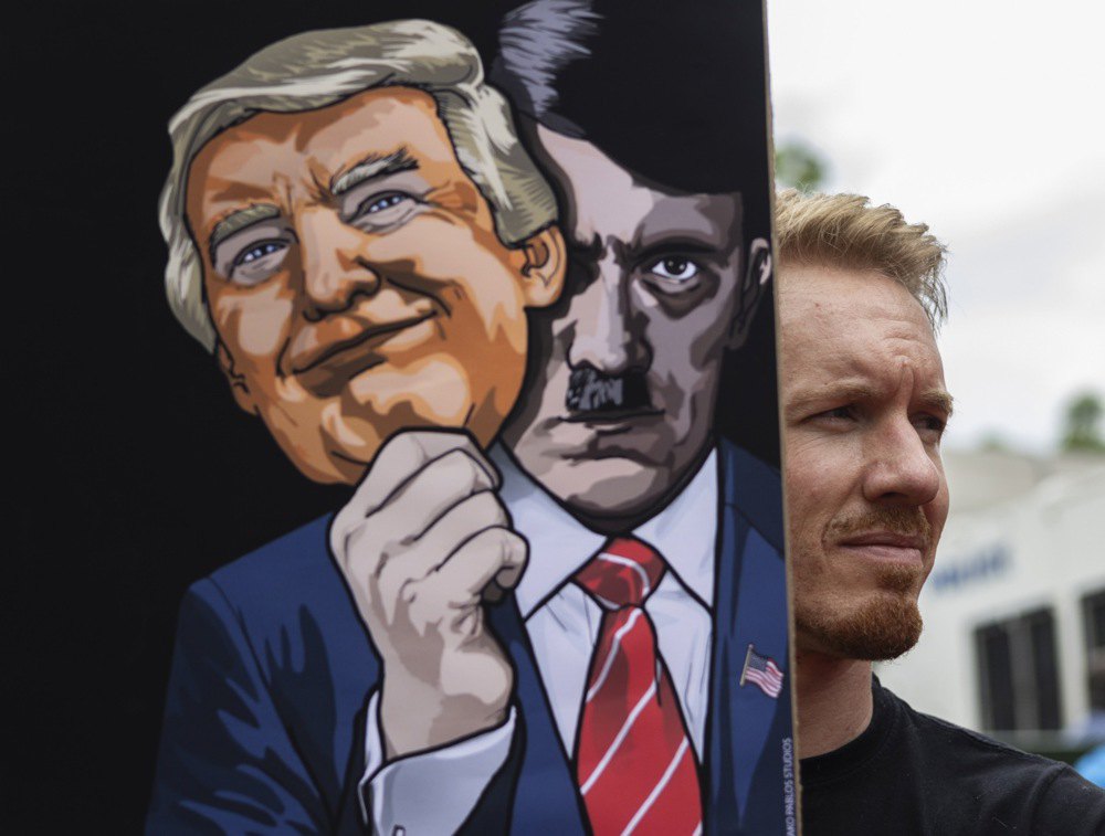 Протестувальник з плакатом із зображенням президента США Дональда Трампа та Адольфа Гітлера біля посольства Сполучених Штатів
під час протесту «Руки геть від Венесуели» в Преторії, Південна Африка, 8 січня 2026 року.