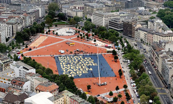 Гігантський плакат, розстелений в центрі Женеви напередодні референдуму з написом <<Що б ви зробили, якби ваш дохід був забезпечений?>>
