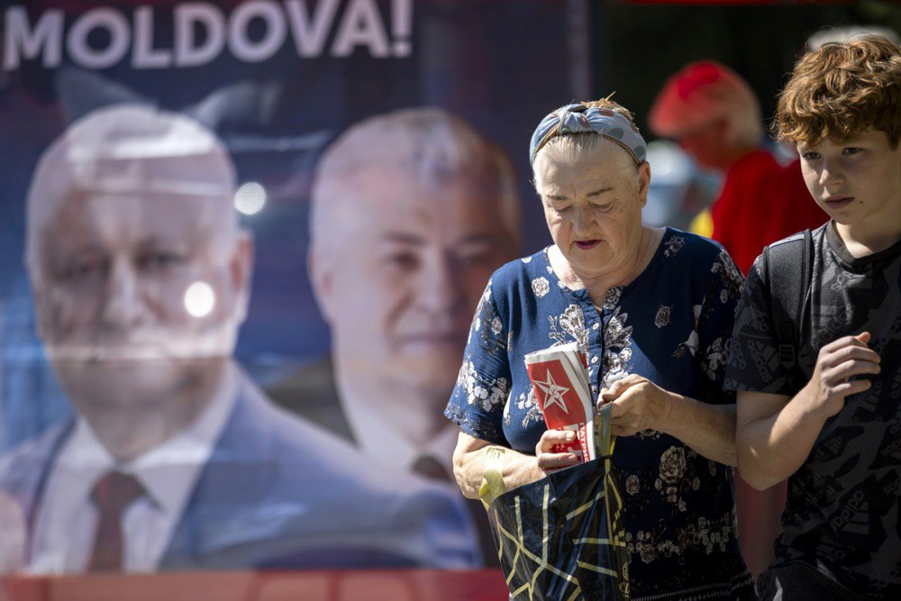 Жінка тримає в руках агітаційну газету біля намету соціалістичної партії у Кишиневі, 5 вересня 2025 року.