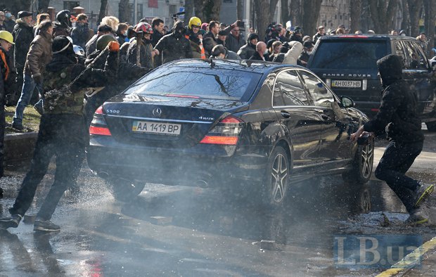 Протестующие бьют стекла автомобиля, который выезжает из офиса ПР