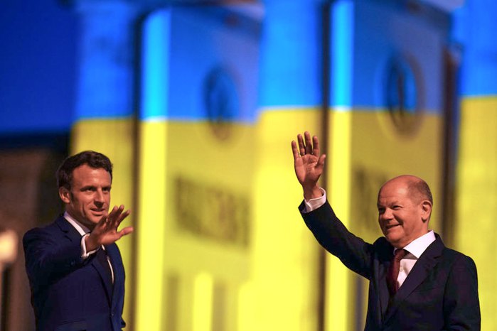 Канцлер Німеччини Олаф Шольц (праворуч) і президент Франції Емманюель Макрон перед Бранденбурзькими воротами, освітленими в національних кольорах України, 9 травня 2022 р.