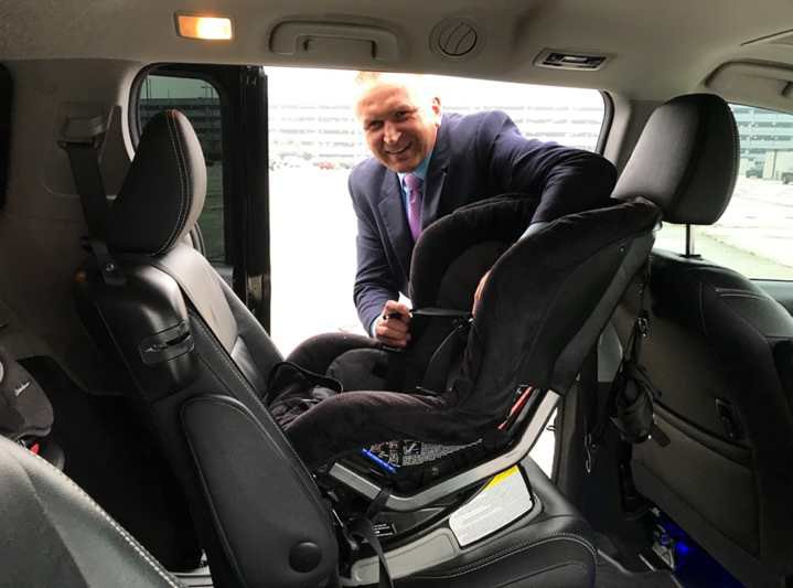 Водій таксі встановлює дитяче автокрісло перед поїздкою, США