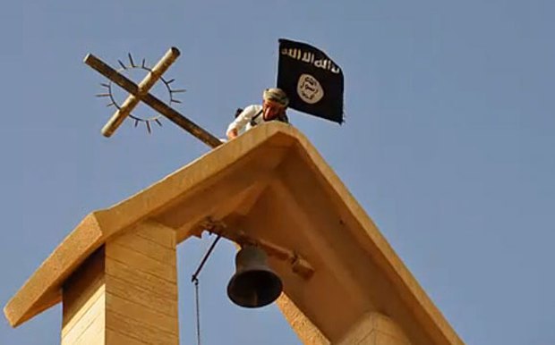 Сторонник ИГИЛ устанавливает флаг Исламского государства вместо хреста на церкви в Ираке