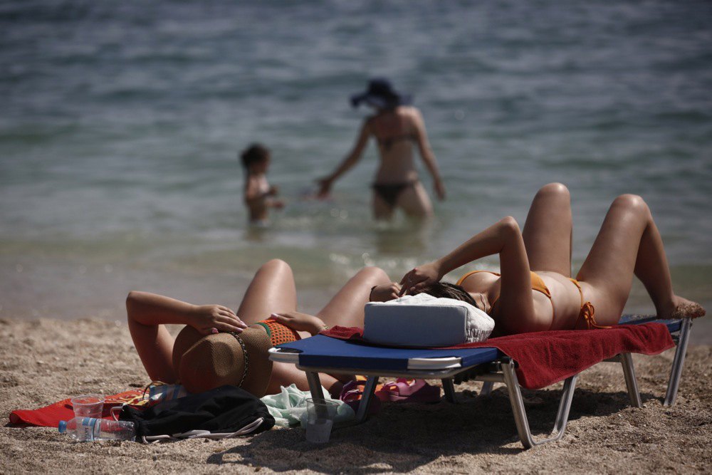 Туристи засмагають на пляжі поблизу Афін