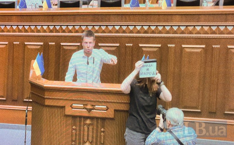 Нардепка Мар’яна Безугла з написом: «Влада — це народ» біля трибуни під час виступу Олексія Гончаренка.