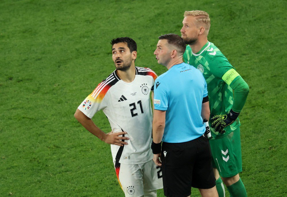Англійський арбітр Майкл Олівер спілкується з Ілкаєм Ґюндоганом (ліворуч) з Німеччини та воротарем Каспером Шмейхелем (праворуч) з Данії перед другим таймом 1/8 фіналу футбольного матчу Євро-2024 між Німеччиною та Данією в Дортмунді, Німеччина.