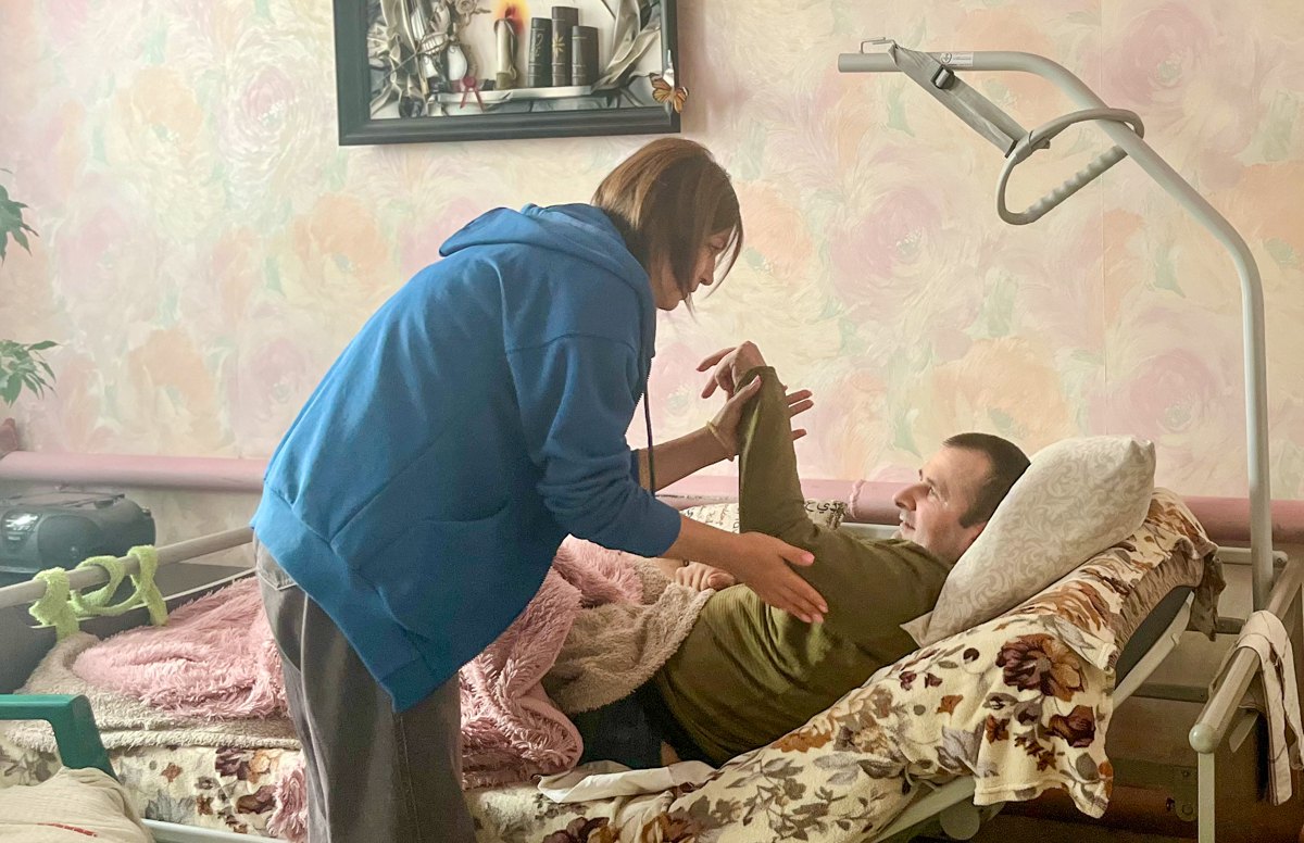 Реабілітологиня Юлія Галунко робить вправи з ветераном Володимиром Фігурним під час реабілітаційного візиту додому.