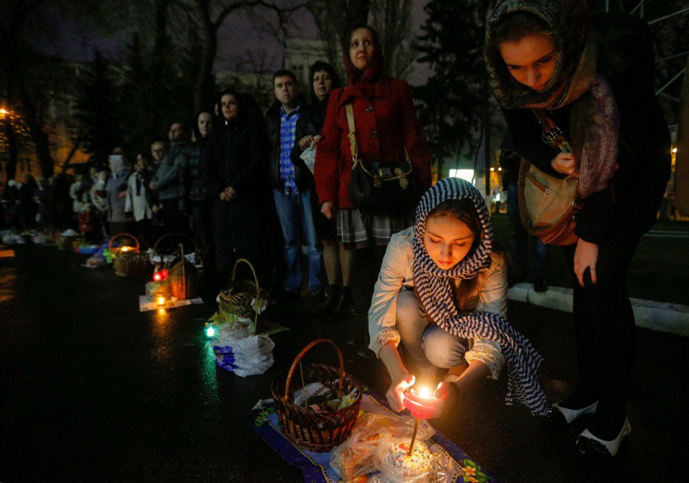 Люди запалюють свічки перед великодньою службою у Володимирському соборі в Києві, 15 квітня 2023 р. 