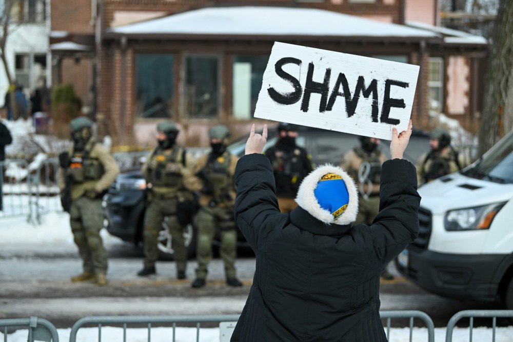 Протестувальник тримає плакат з написом СОРОМ на місці патрулювання агентами місця події, де було застрелено жінку агентом ICE у Міннеаполісі, штат Міннесота, 7 січня 2026 року.
