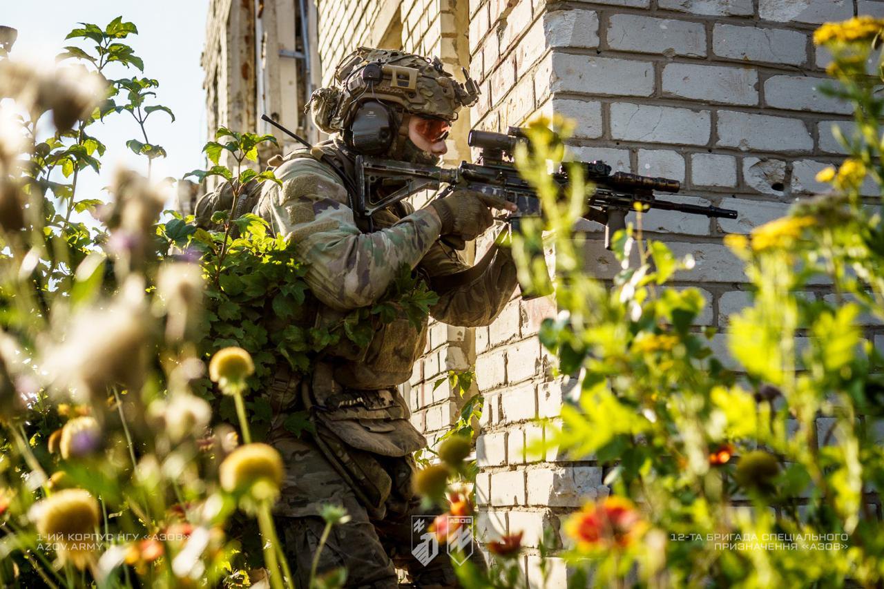 Боєць 12-ї бригади спеціального призначення «Азов» веде роботу в зеленій зоні біля будівлі під час виконання
завдання