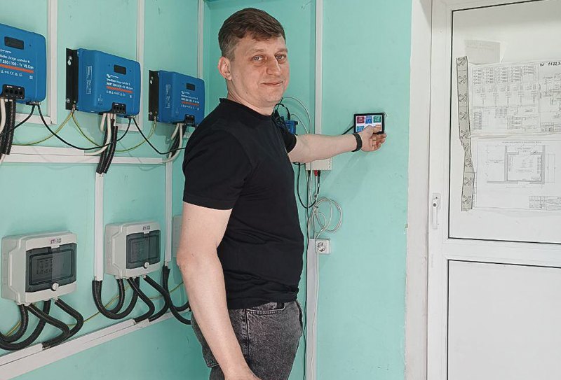 Денис Скоренко біля монітора, який показує рівень генерації та розподіл електроенергії