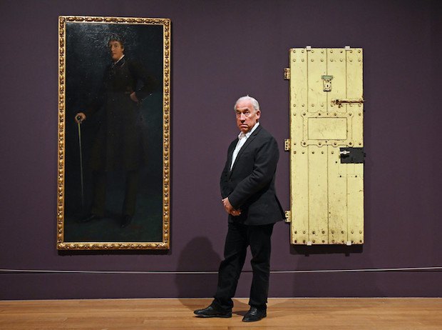 Актер Саймон Коллоу на фоне портрета Оскара Уайльда и двери его тюремной камеры
