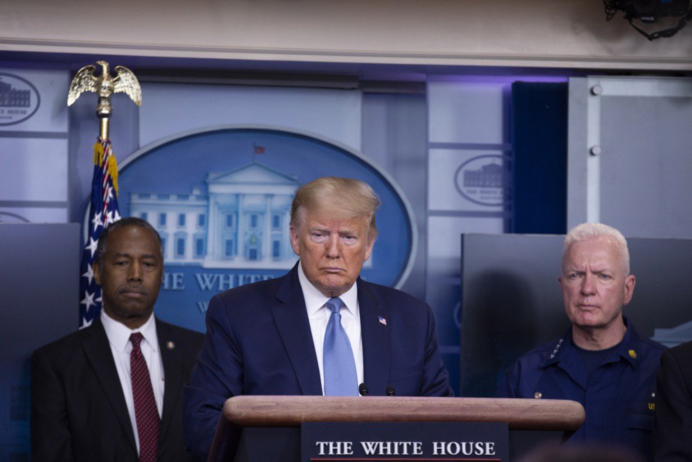 Дональд Трамп виступає в Білому домі щодо пандемії <i>COVID-19</i>, 21 березня 2020 р. Ліворуч — Бен Карсон, праворуч — адмірал Бретт Гіруар, помічник міністра охорони здоров’я