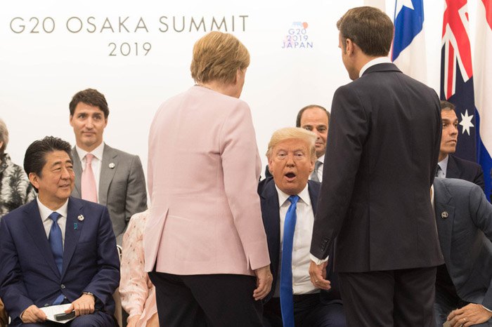 Президент США Дональд Трамп (в центрі), канцлер Німеччини Ангела Меркель (спиною зліва) і президент Франції
Емануель Макрон (спиною справа) спілкуються під час зустрічі лідерів G20 на саміті в Осаці, Японія, 29 червня 2019.