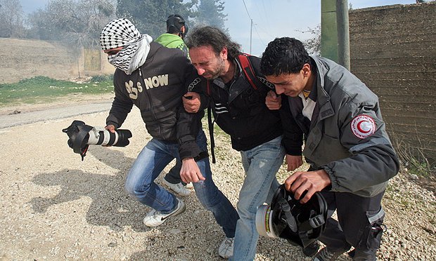 Палестинцы помогают покинуть место боя израильскому фотографу