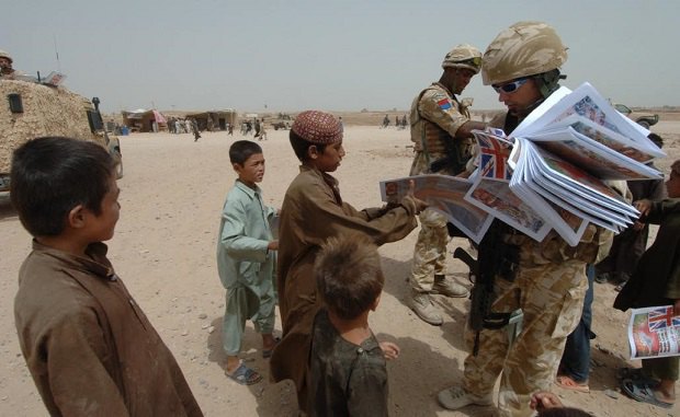 Бойцы подразделения специальных информопераций раздают газеты местным жителям во время одного из конфликтов на Ближнем Востоке