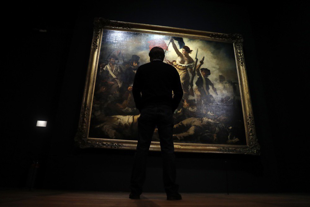 Відвідувач розглядає картину французького художника Ежена Делакруа під назвою «Свобода веде народ» в Луврі.