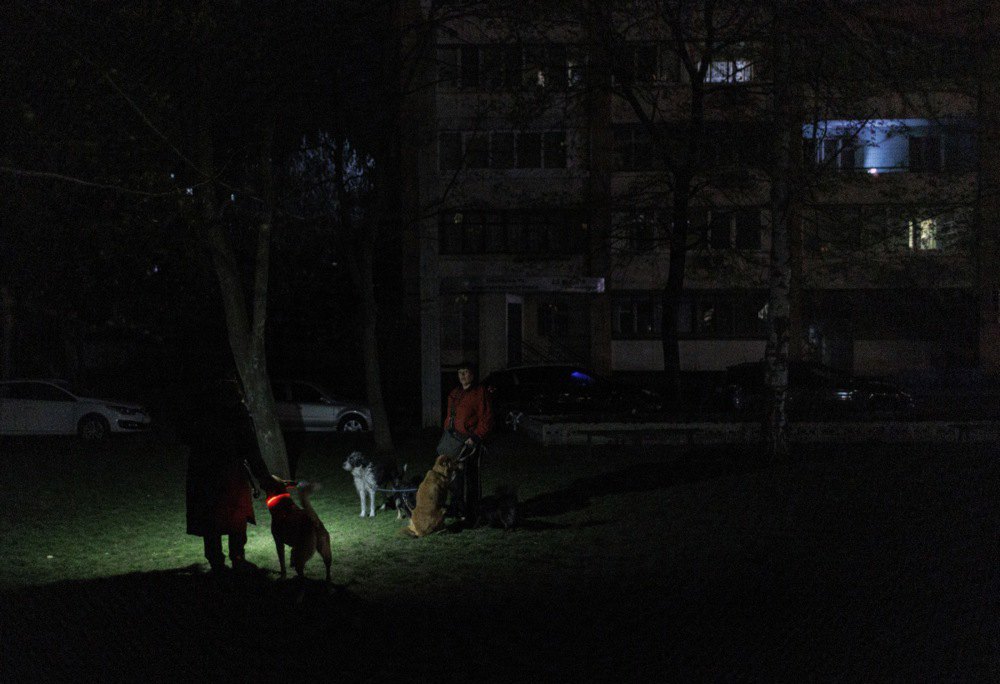 Люди вигулюють собак у дворі під час відключення електроенергії в Харкові, 7 квітня 2024 року