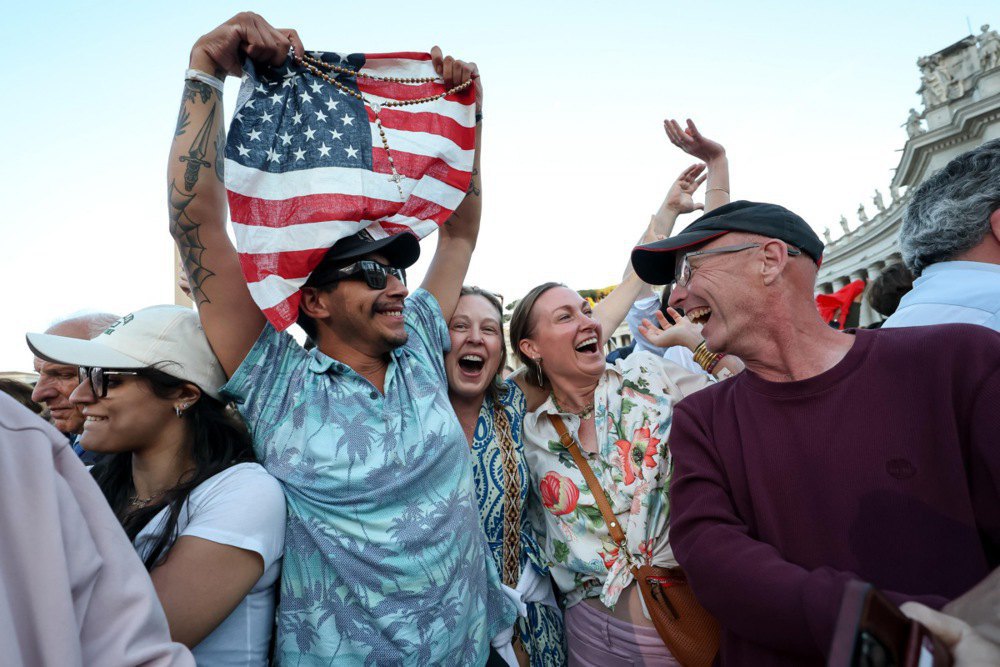 Faithful with the US flag cheer after the announcement of the new Pope Leo XIV in St Peter's Square in Vatican City, 8 May 2025.