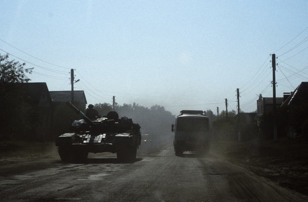 A civilian bus passes a Ukrainian tank on the road in the village of Yunakivka, 9 kilometers from the border with Russia in Sumy Region.