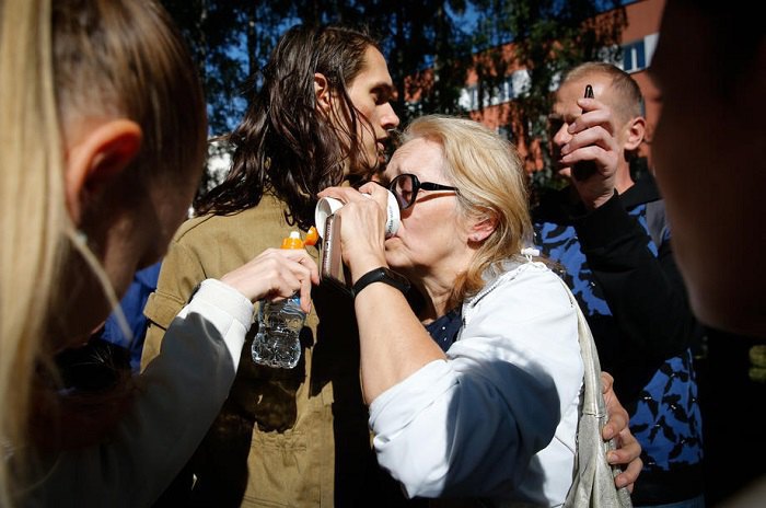 A woman drinks water after being released from a pre-trial detention centre in Minsk
