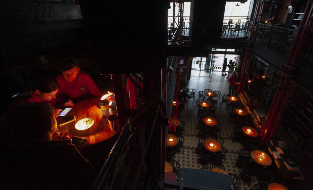 Visitors to a cafe that is lit with candles during the power outage in Lviv